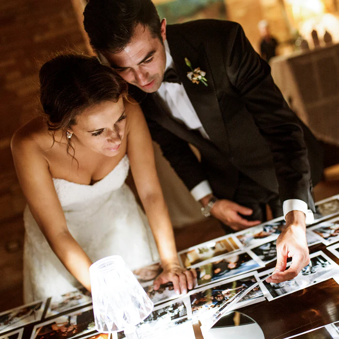 The bride and groom looking through the prints of their day laid out on a table