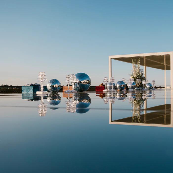 The Wow Box setting at dusk, reflected as in a mirror: disco balls, lamps, boxes and a white pergola