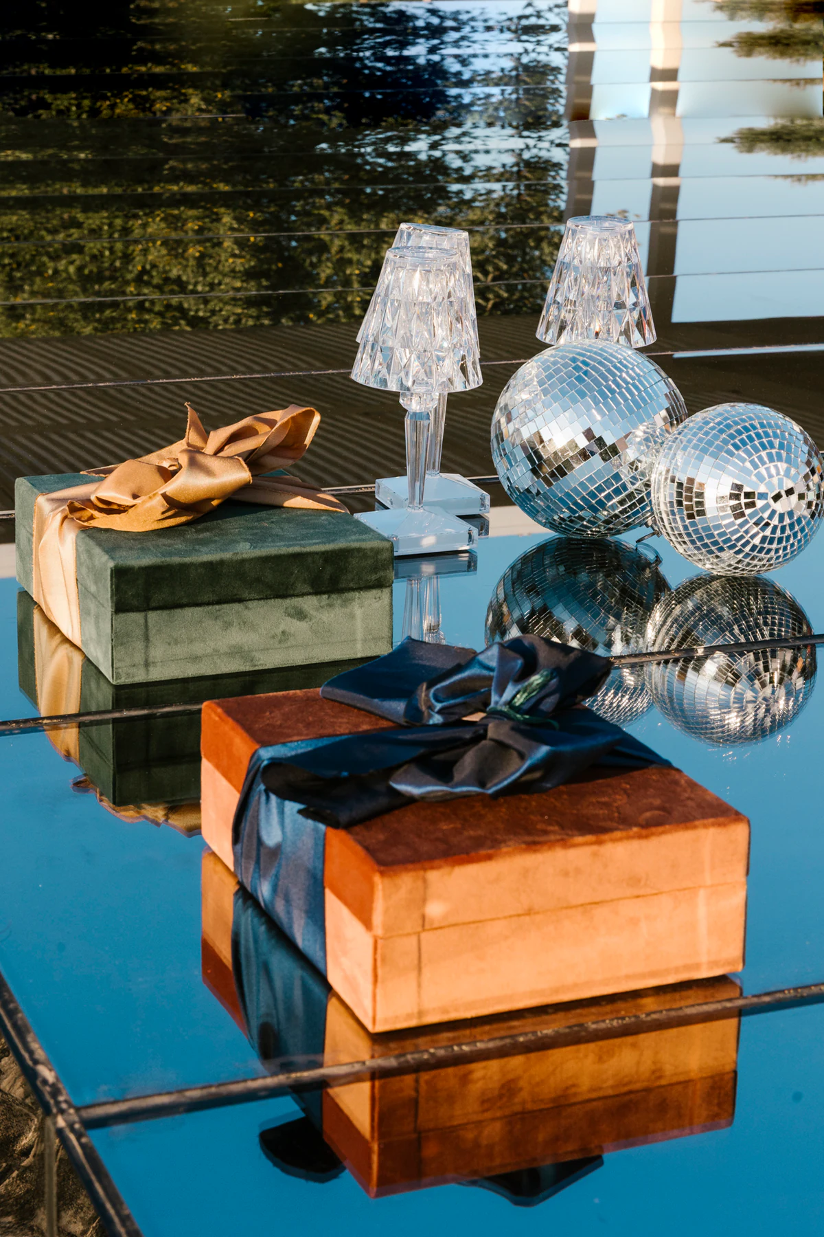Two velvet Wow Boxes tied with satin bows, on a mirror among disco balls and crystal lamps