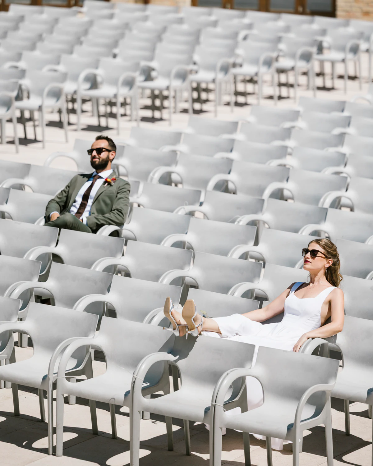 A man and a woman in sunglasses lounging among rows of white chairs