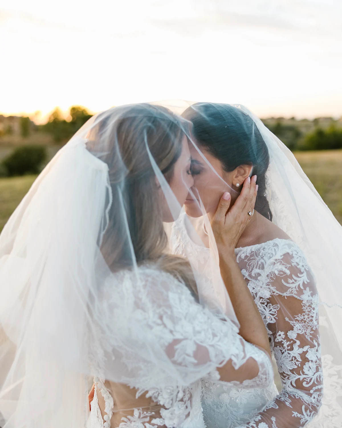 Two brides kissing beneath their veils