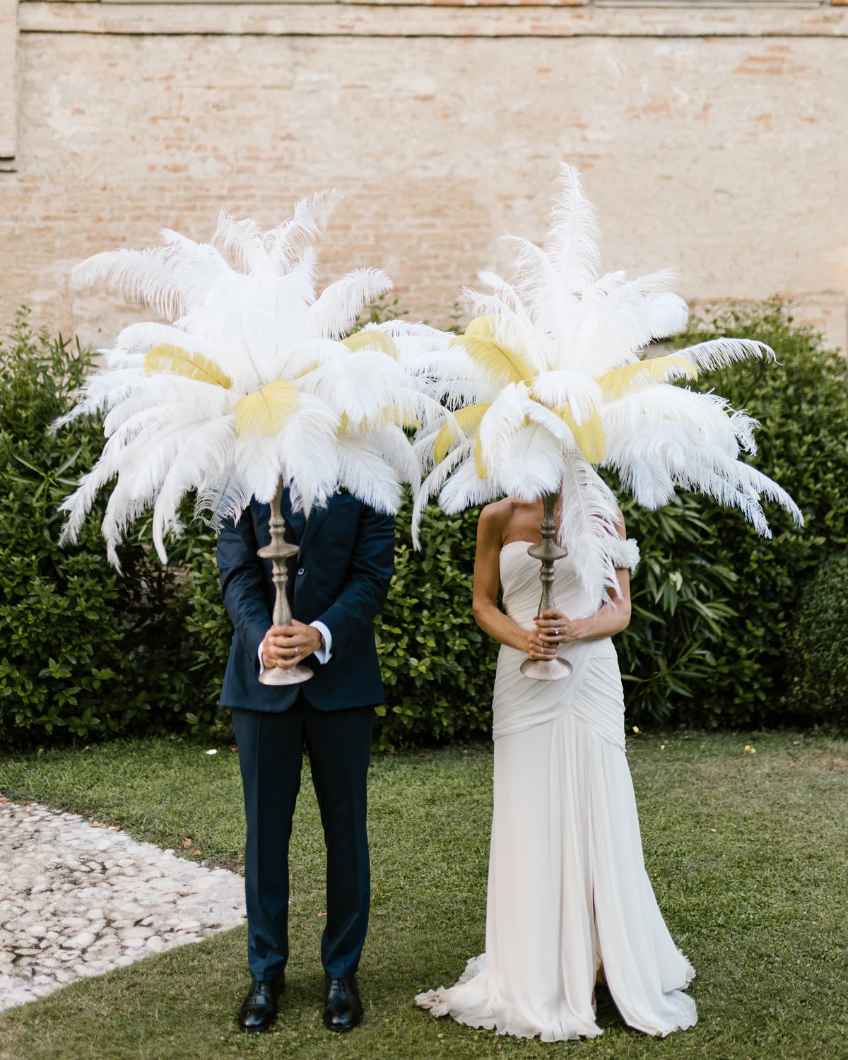 A couple hiding their faces behind white feather plumes