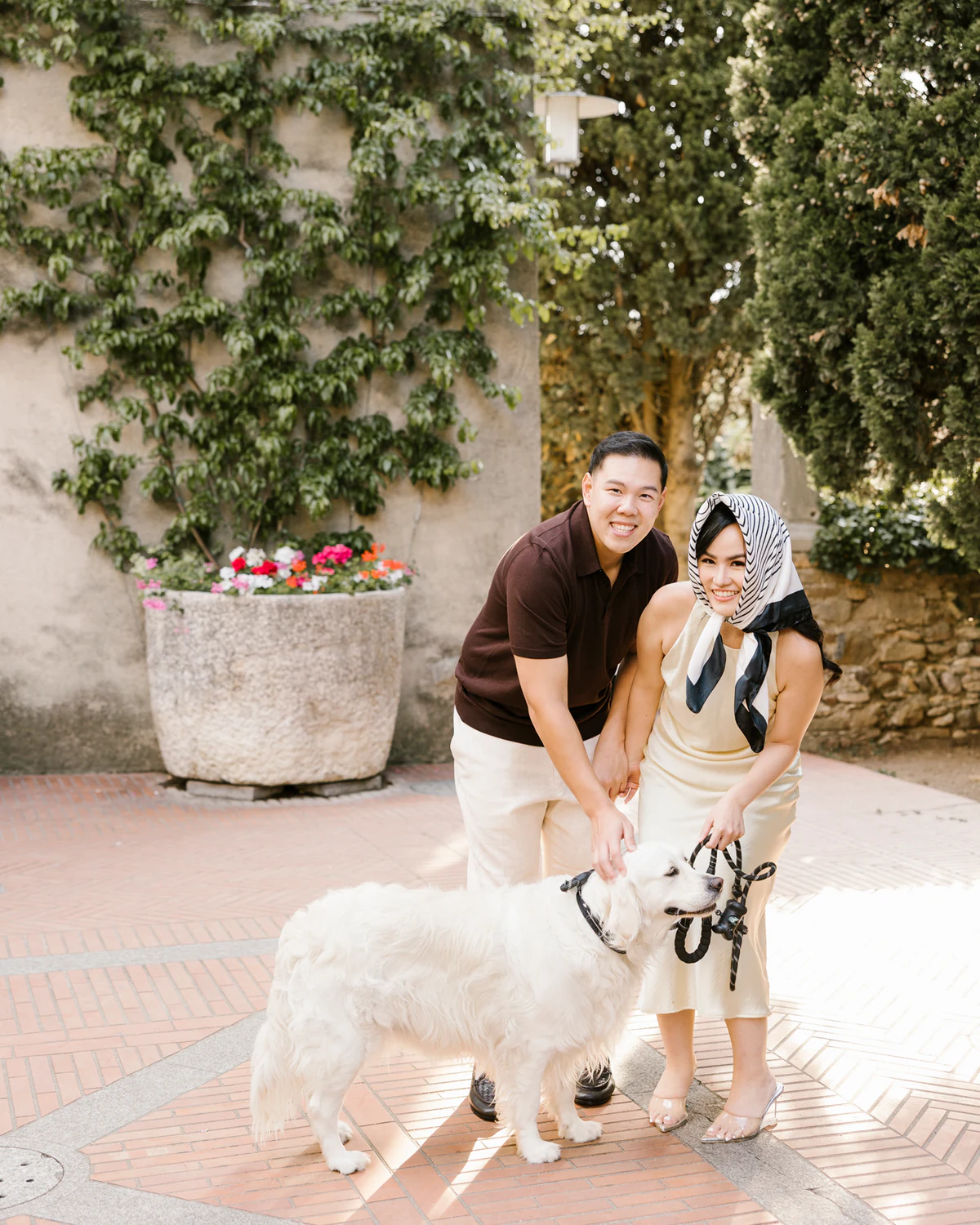 A couple with a large white dog in a courtyard