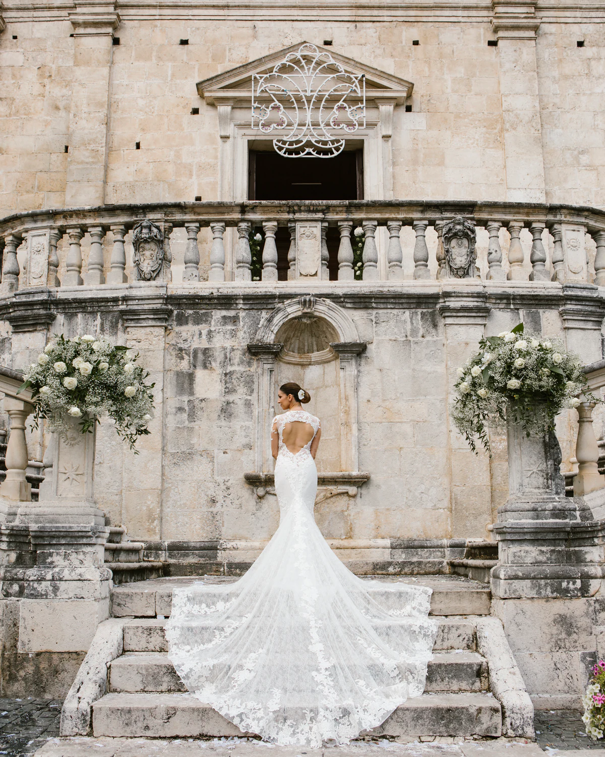 A bride with a long train on the steps of a Baroque façade