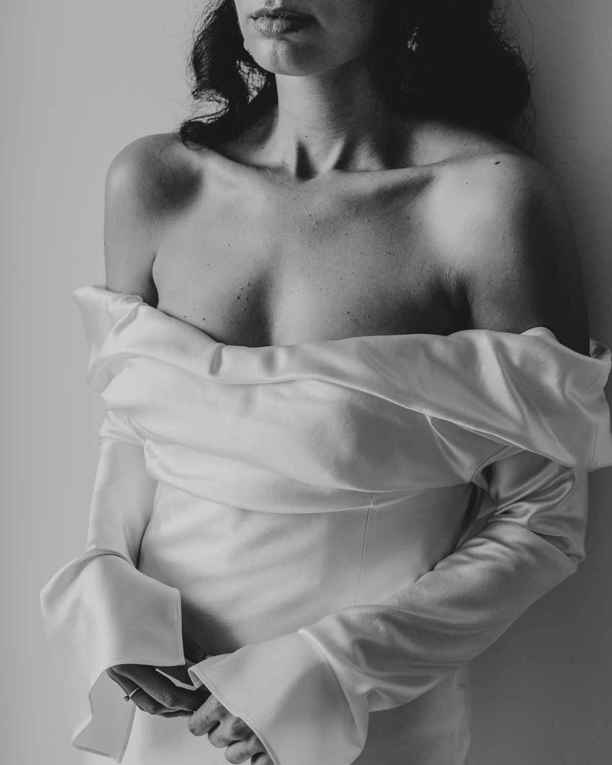 A woman in an off-the-shoulder satin gown, in black and white