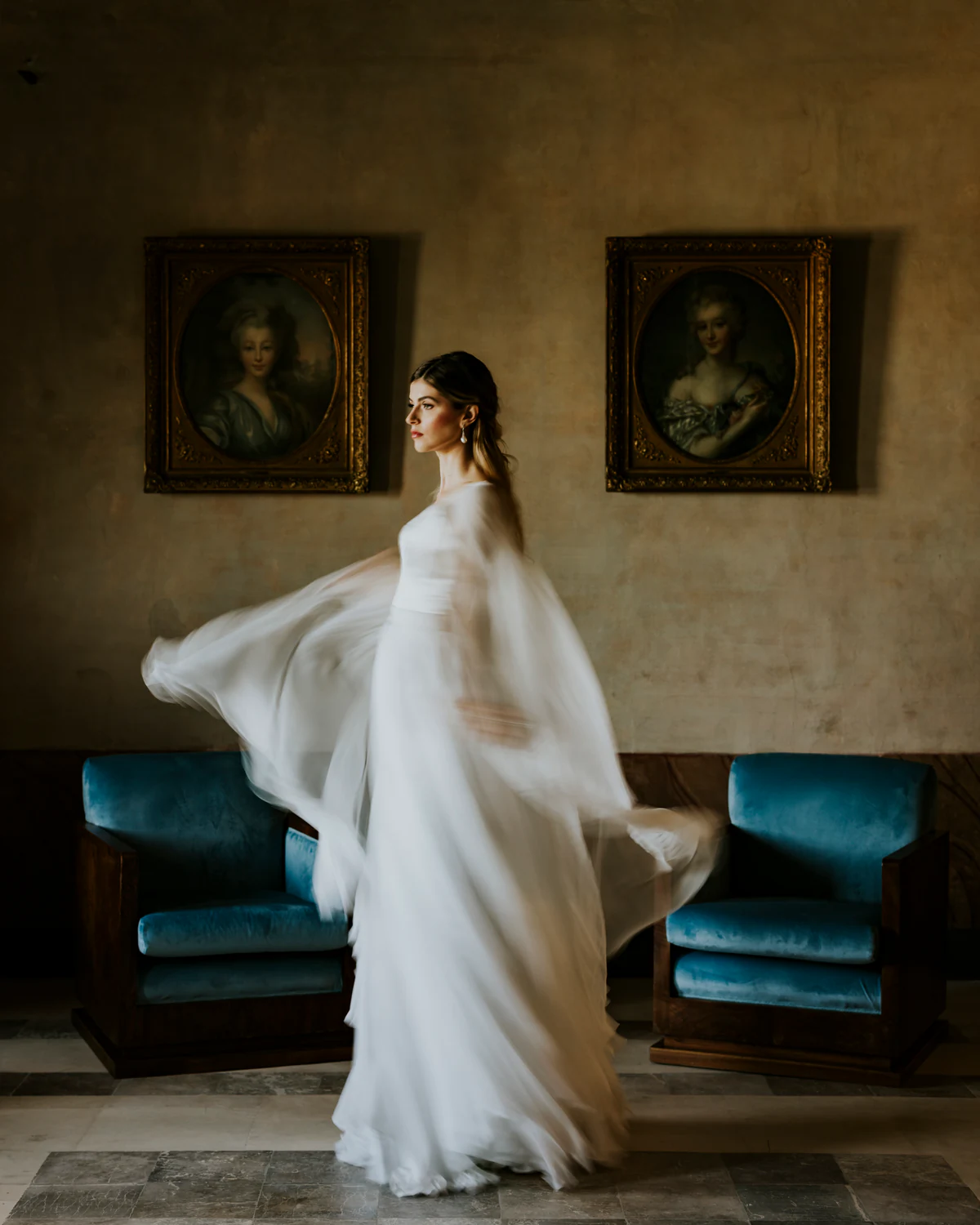 The bride turning, her dress opening, in a room hung with paintings