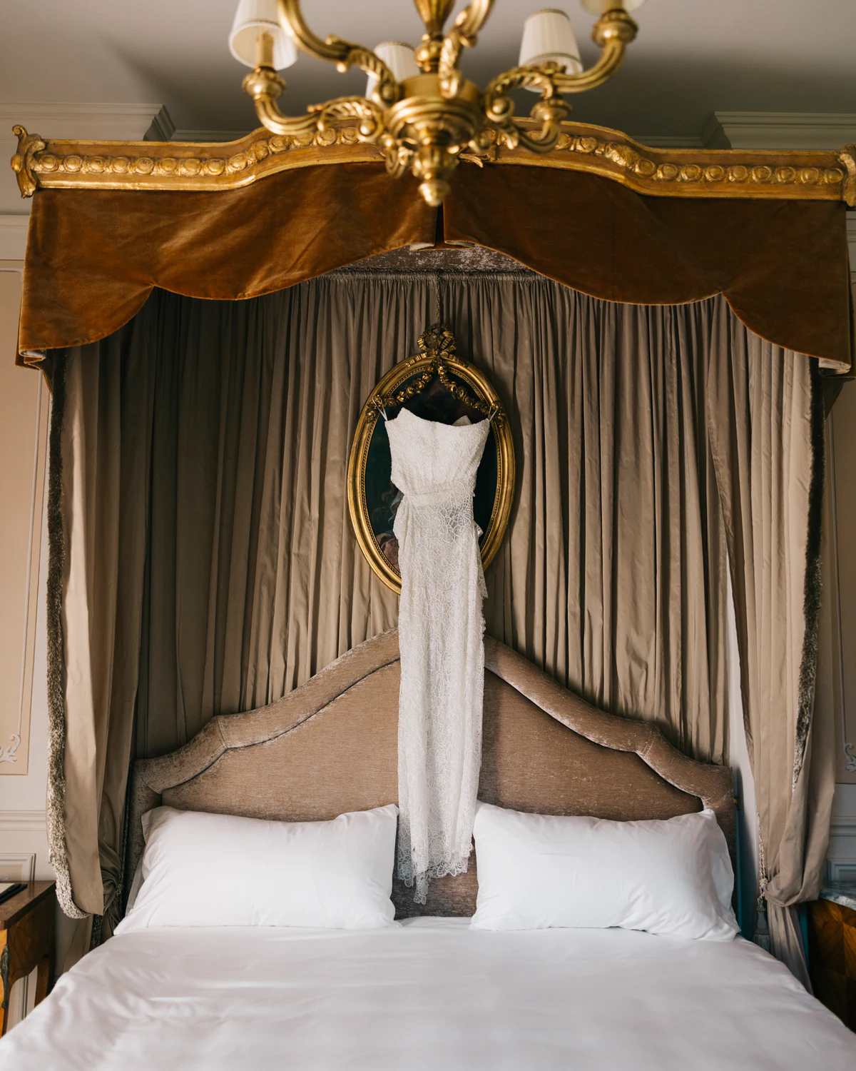 The wedding dress hanging from a canopy bed