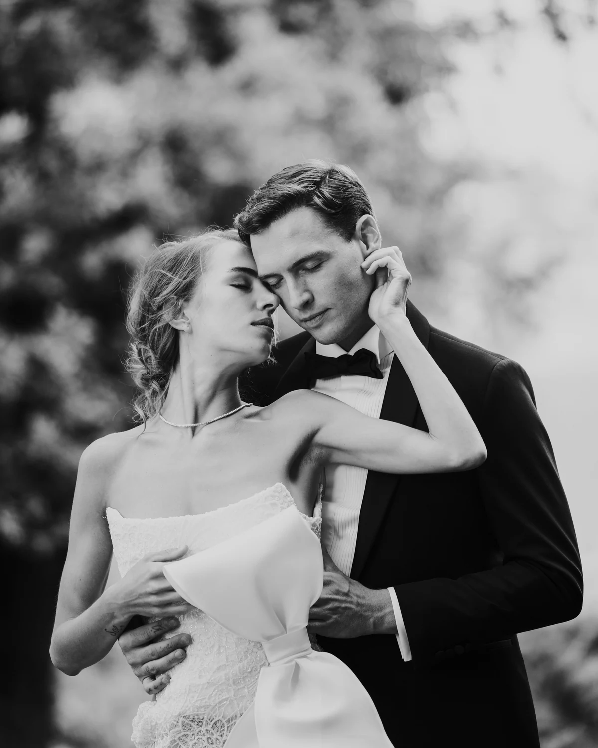 Bride and groom embracing among the trees, in black and white