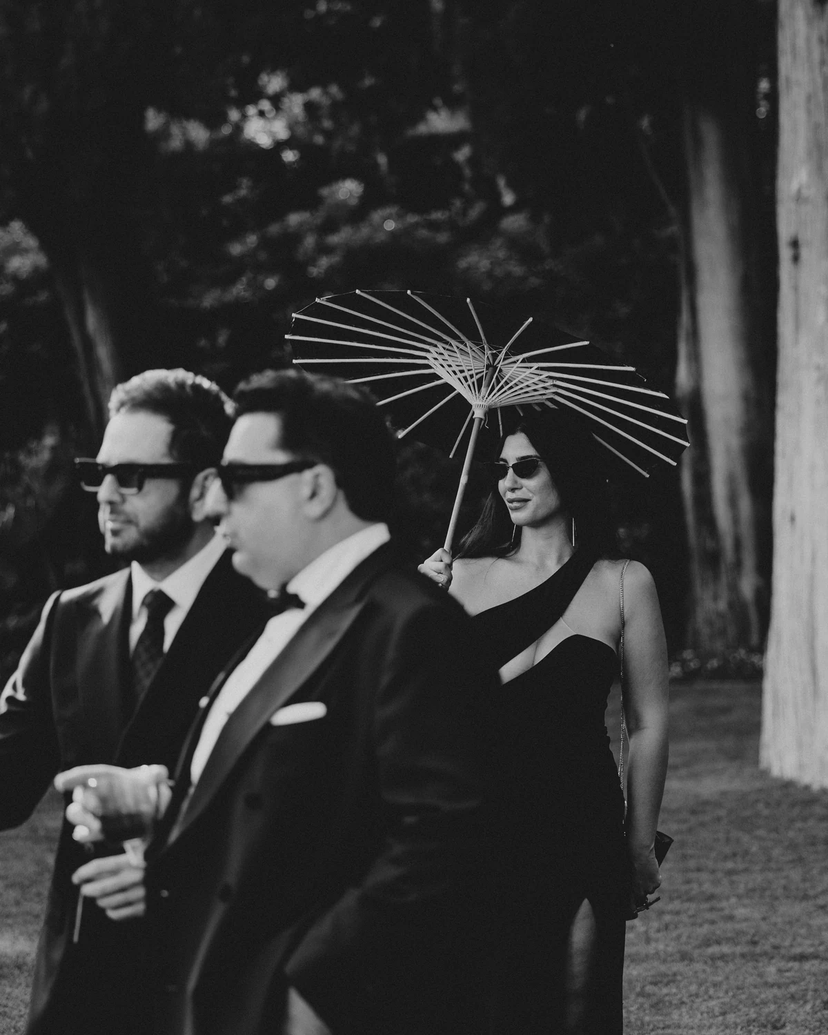 Three guests walking with a parasol, in black and white