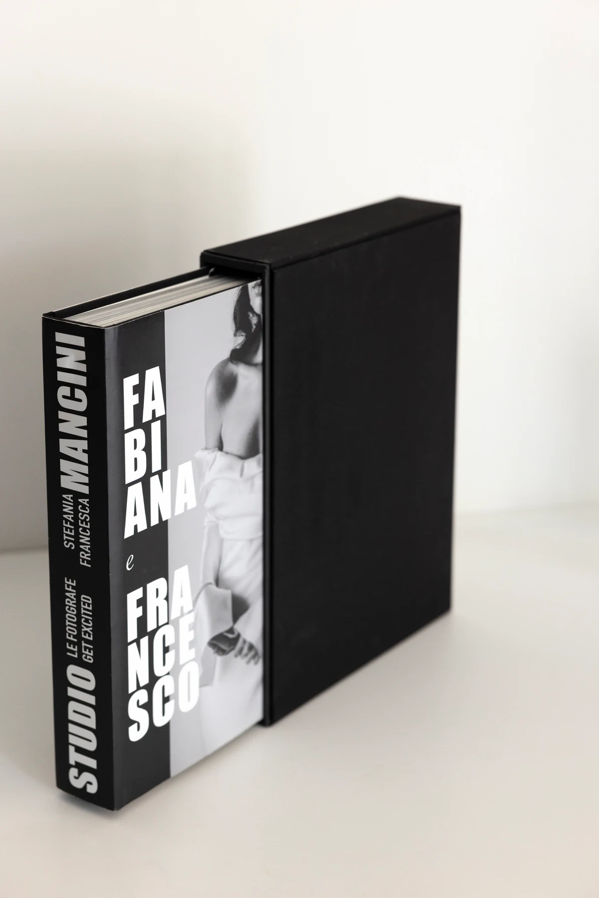 The Editorial Album sliding out of its black slipcase, the spine reading Studio Le Fotografe