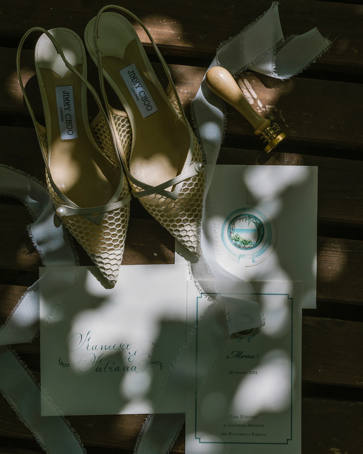 The bride's shoes and the invitation in dappled light