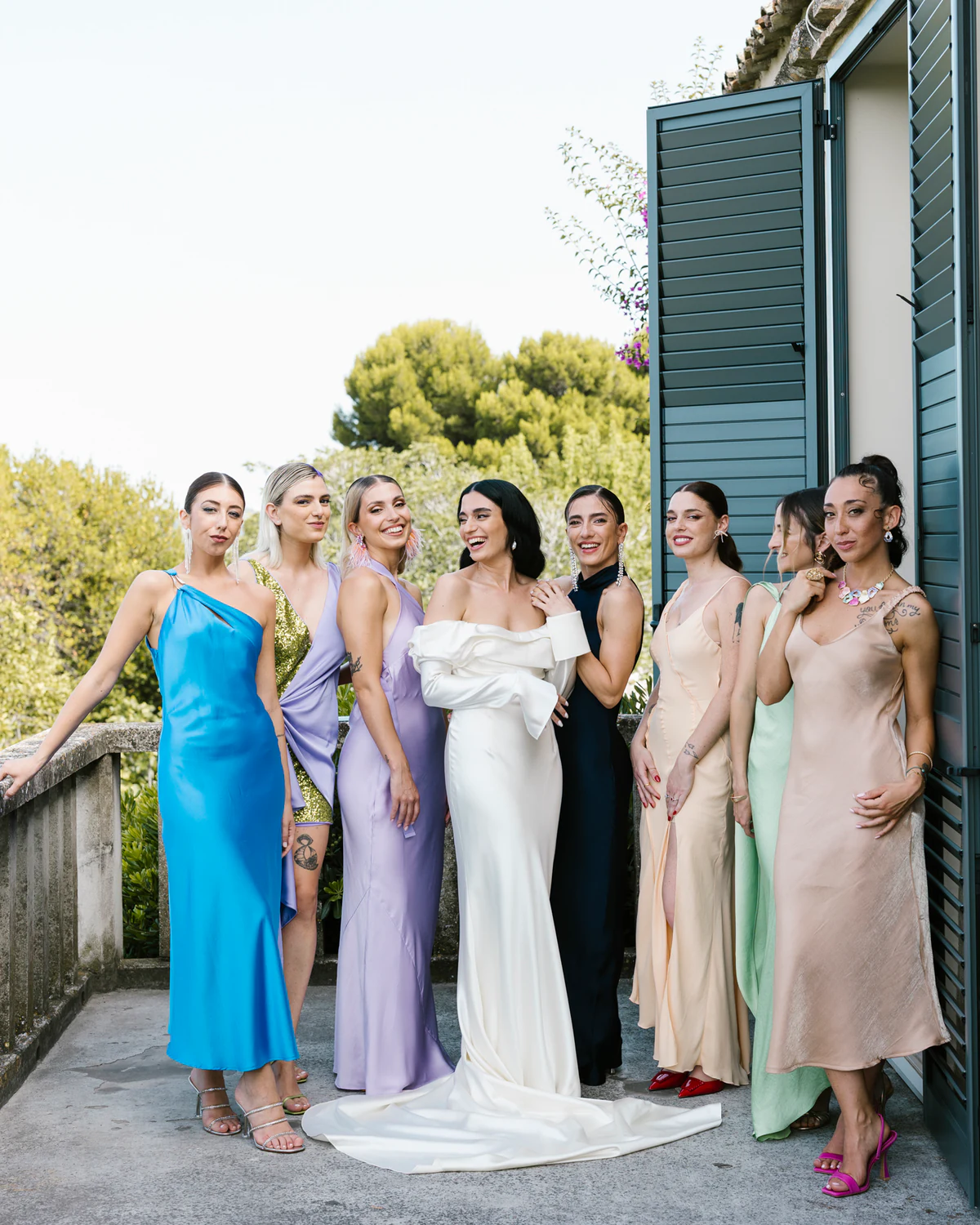 The bride with her bridesmaids in pastel dresses on a balcony