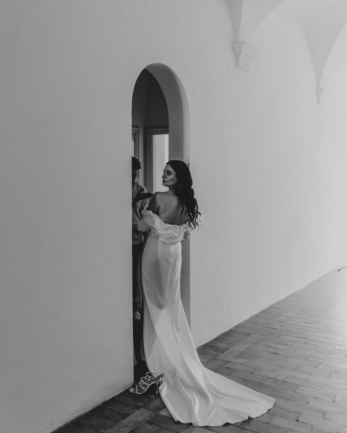 The bride walking alone through an arched doorway