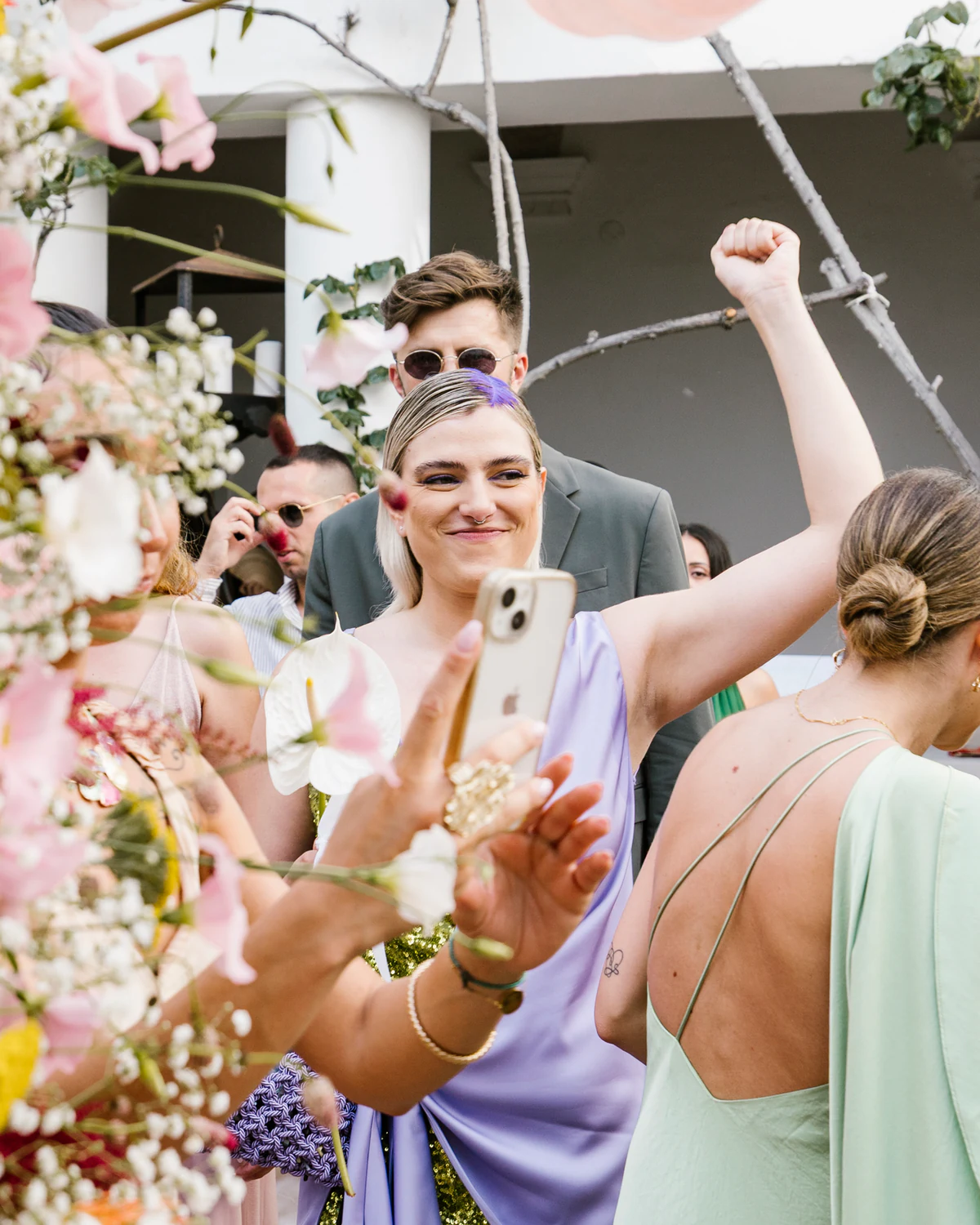 A guest cheering with her arms raised among the flowers