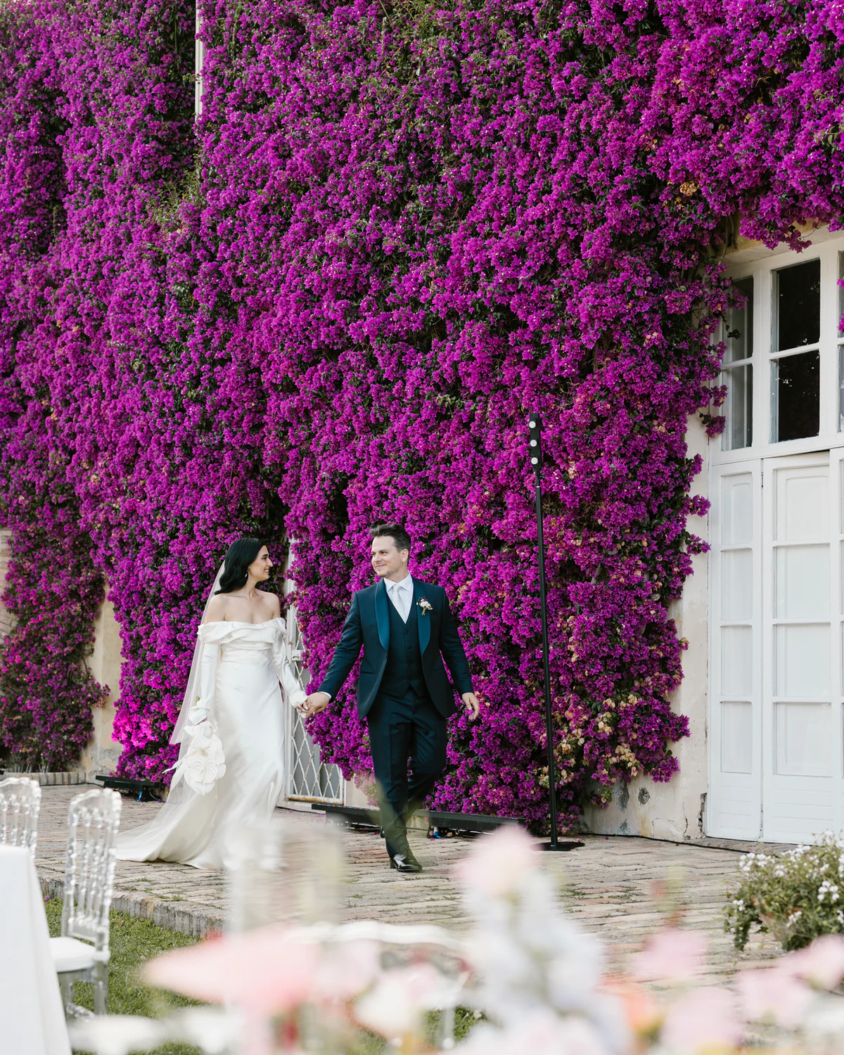 The couple walking in front of the bougainvillea