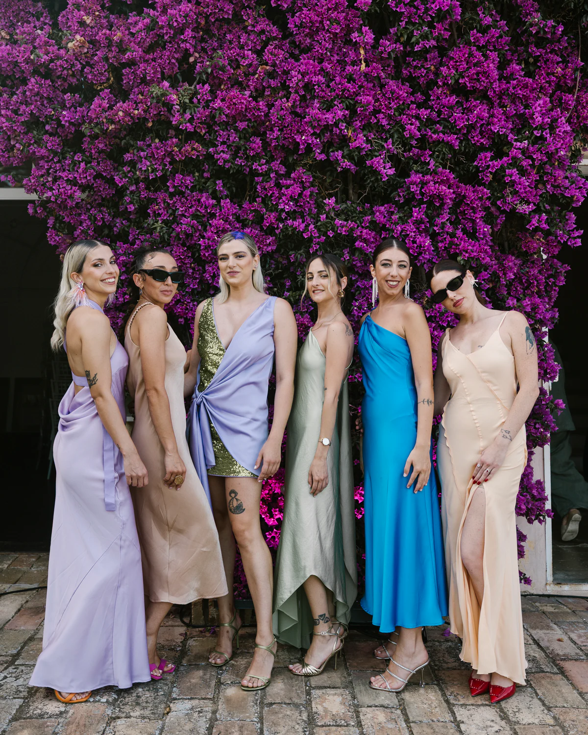 The bridesmaids in pastel dresses under the bougainvillea