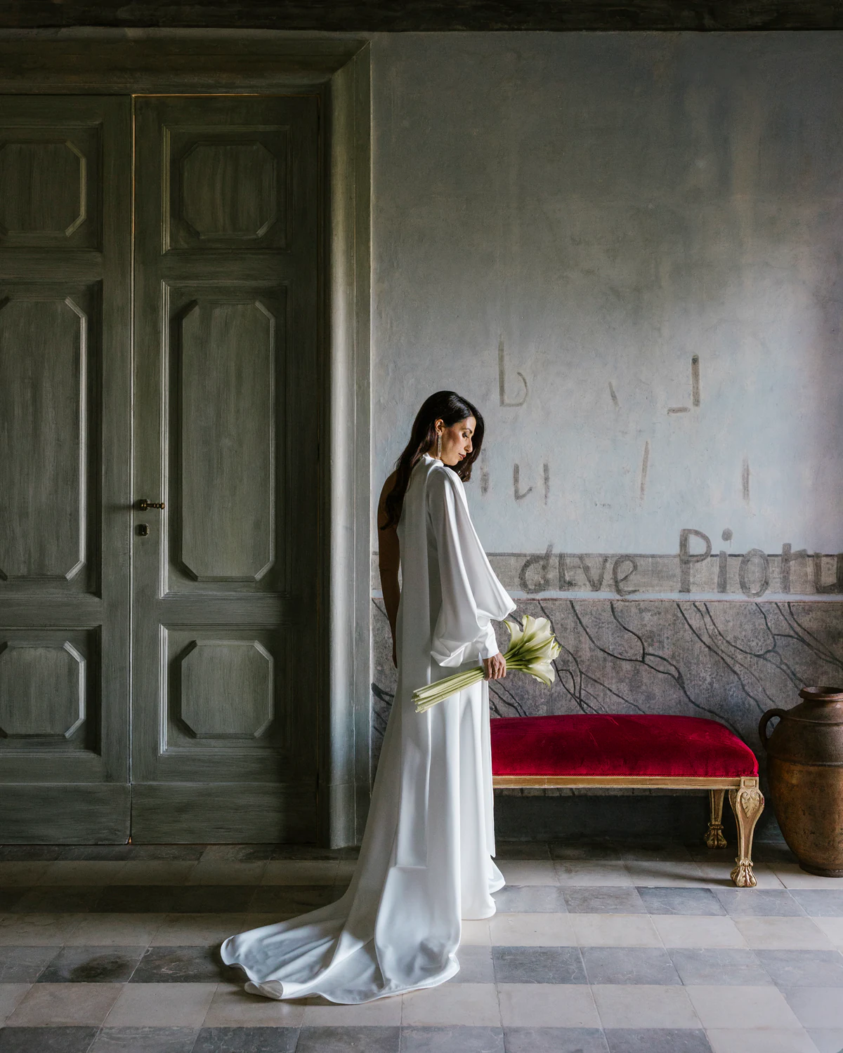 The bride in a bare room with a red velvet bench