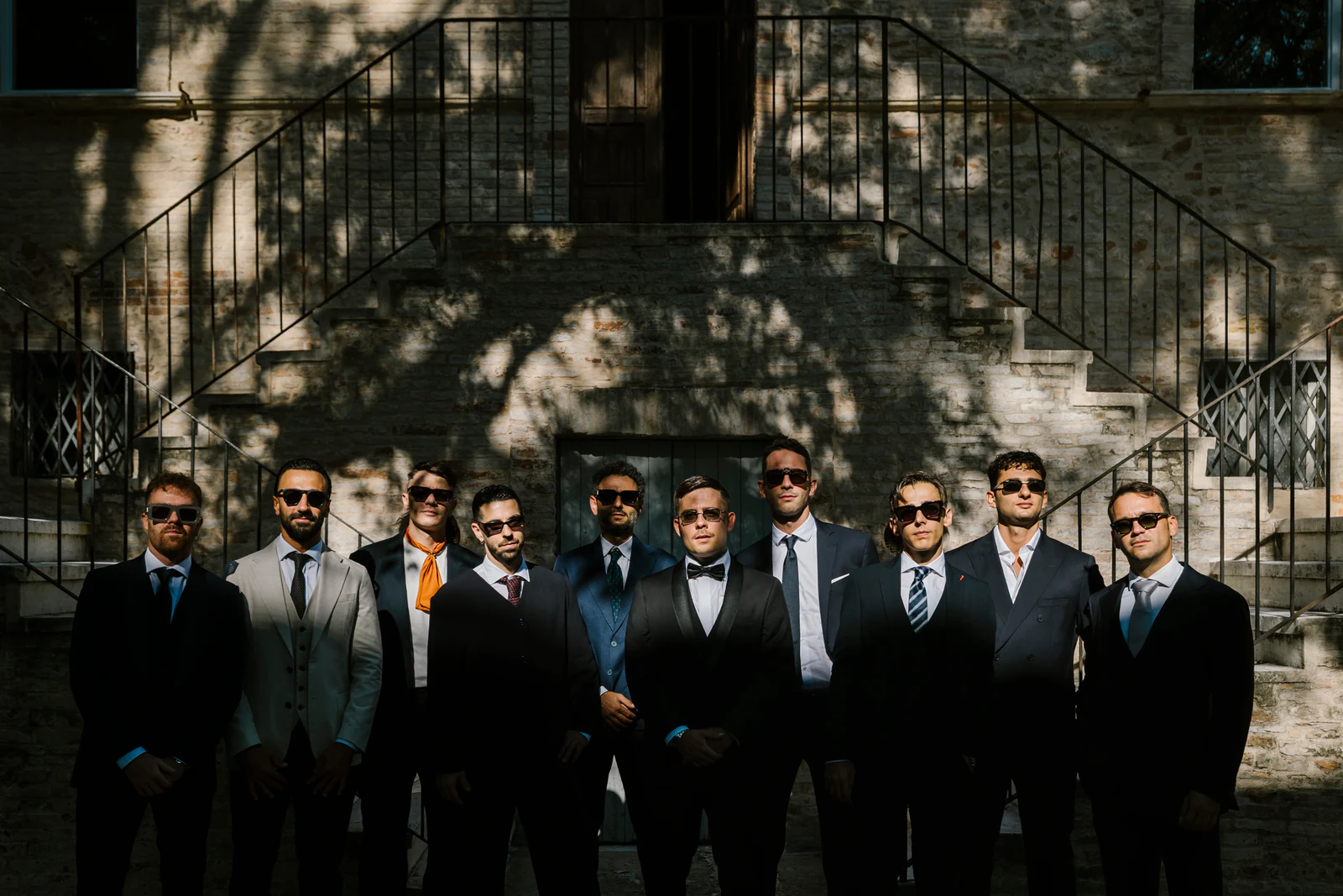 The groom and his friends in dark suits and sunglasses in front of the house