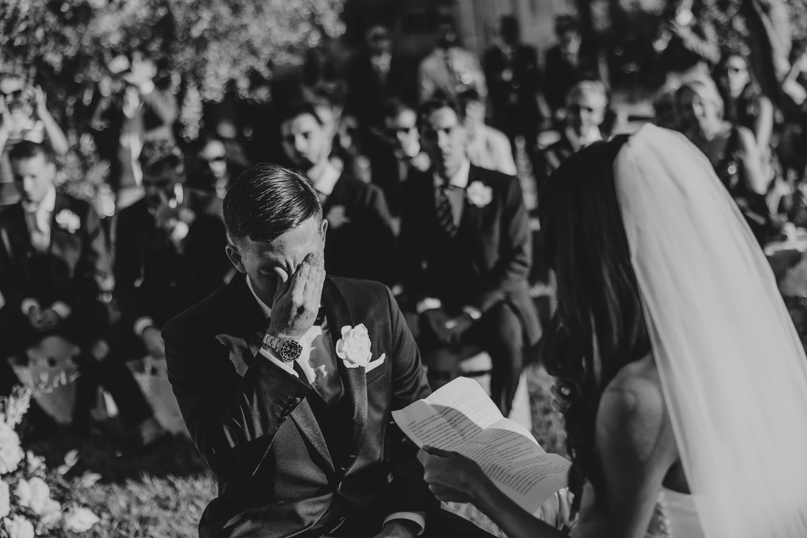 The groom reading his vows beside the bride's veil
