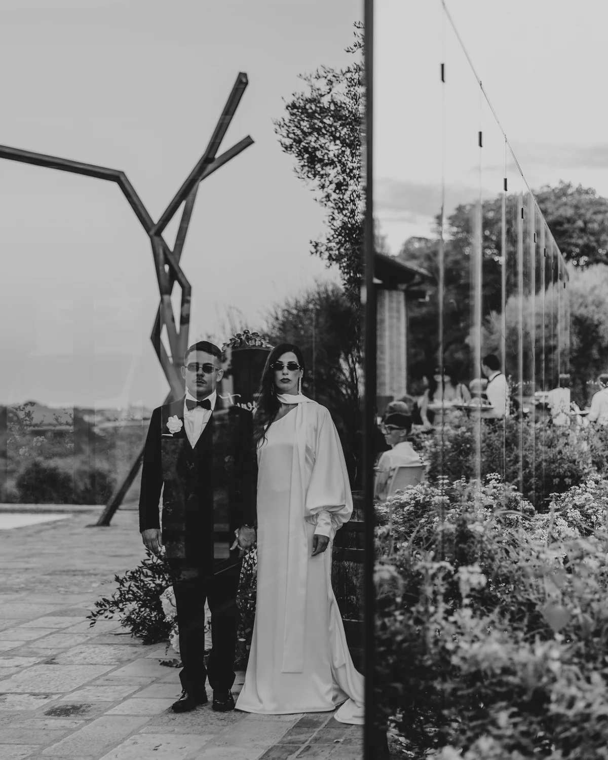 The couple in sunglasses beside a steel sculpture