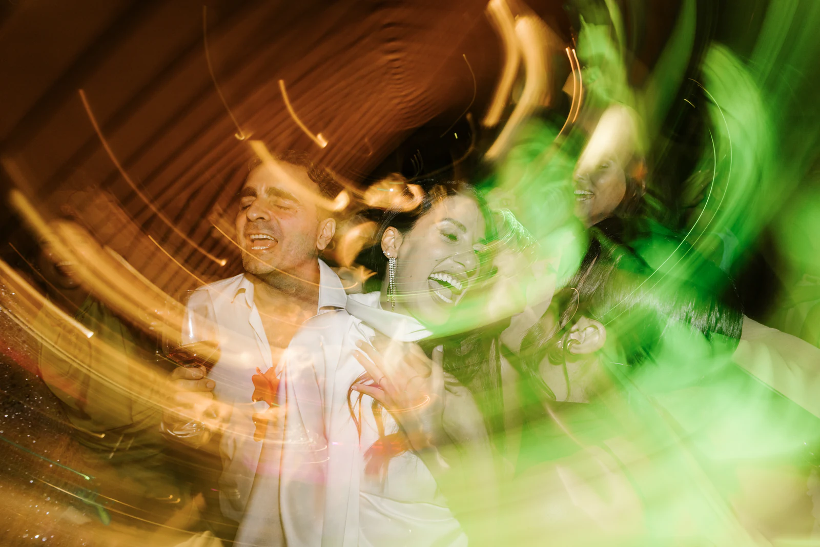 Guests dancing in streaks of orange and green light