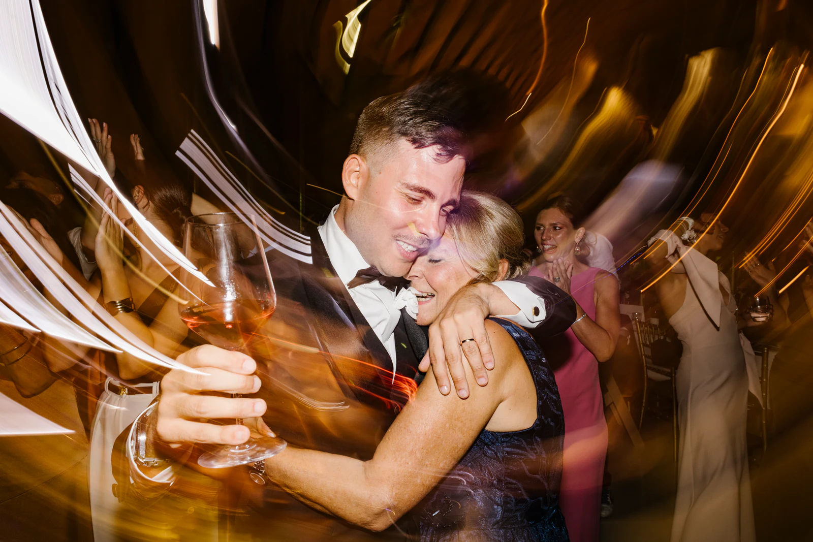 The groom embracing a guest, a glass in his hand