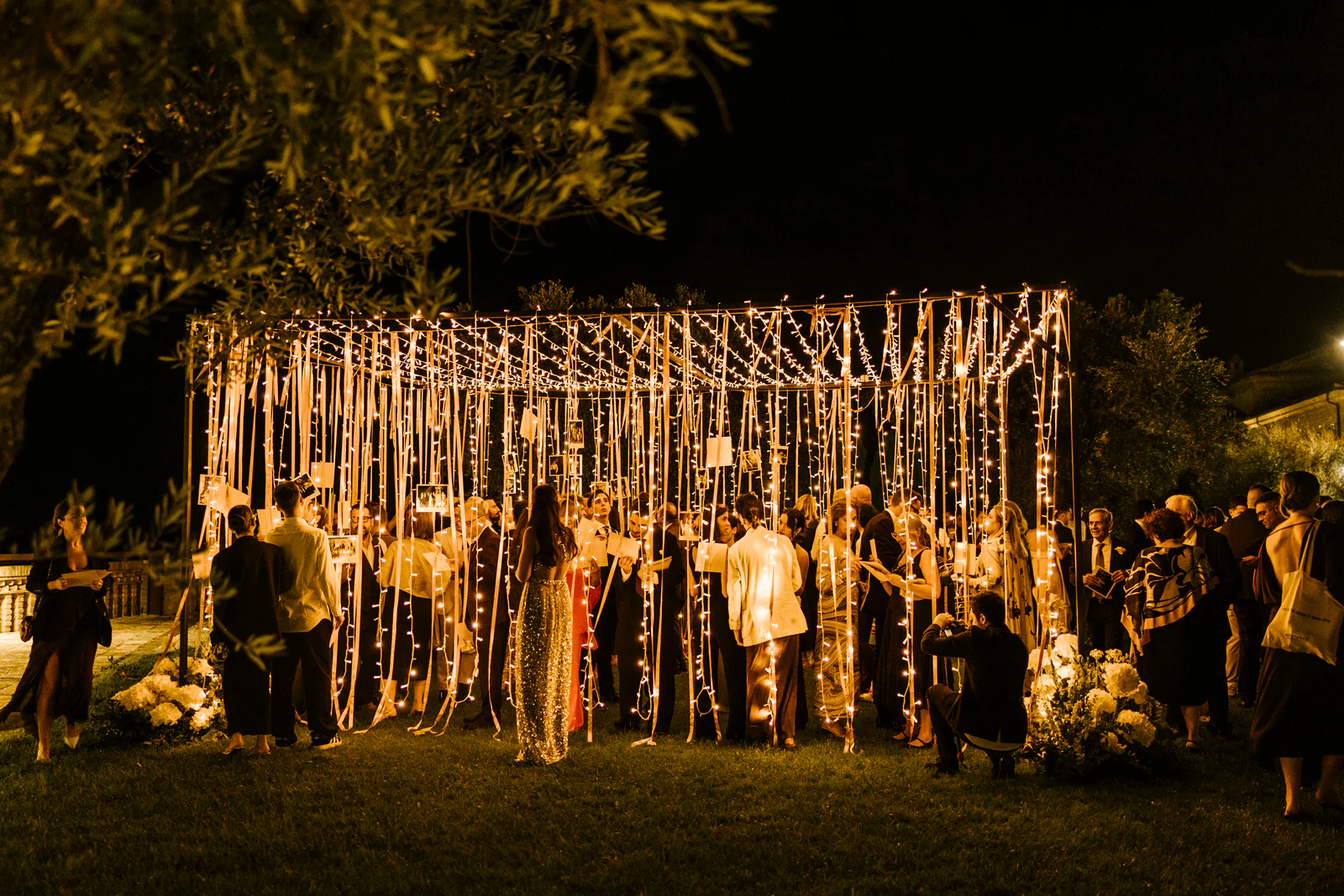 A pavilion of hanging lights in the garden at night