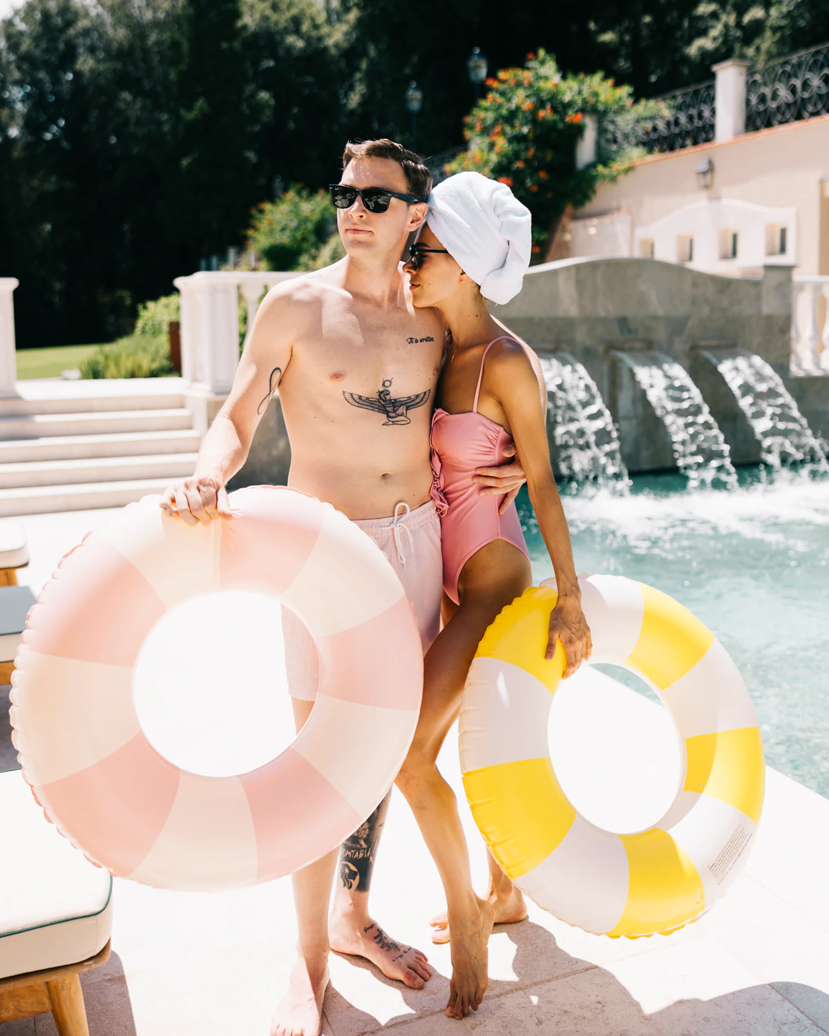 The couple in swimwear by the pool, with inflatable rings