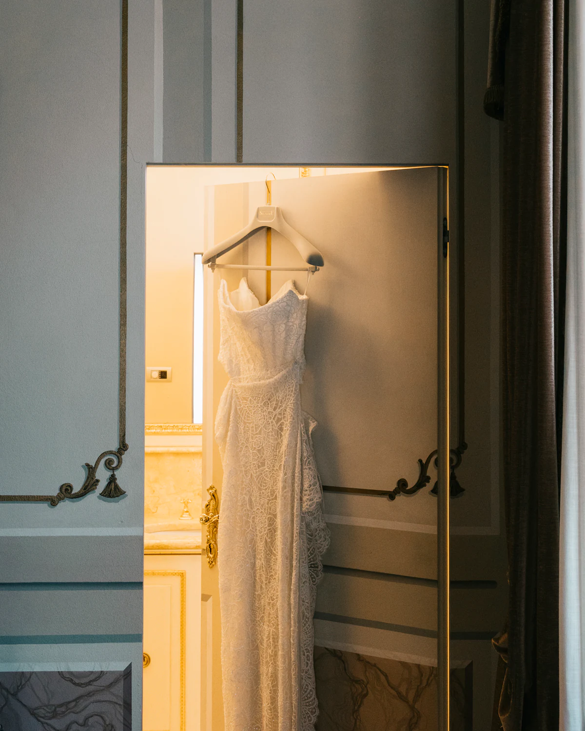The wedding dress hanging on a door in the sunlight