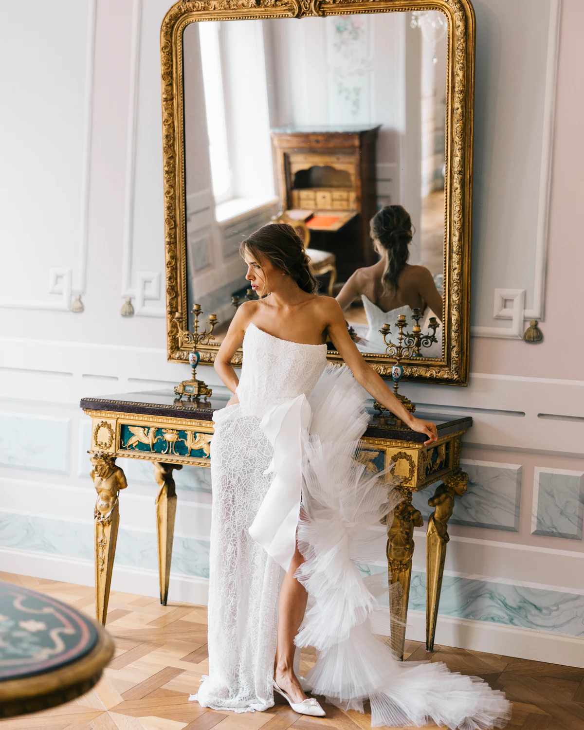 The bride before a gilded mirror in a frescoed room