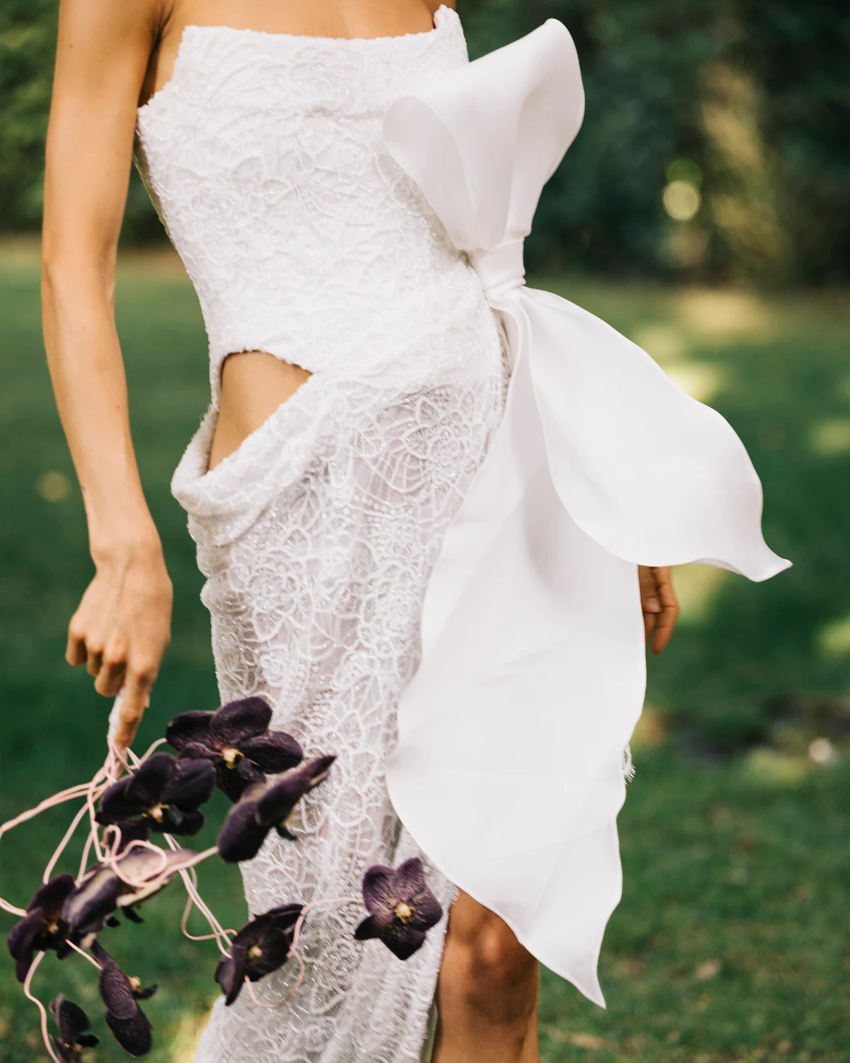 The bride's dress with a large bow, and dark orchids
