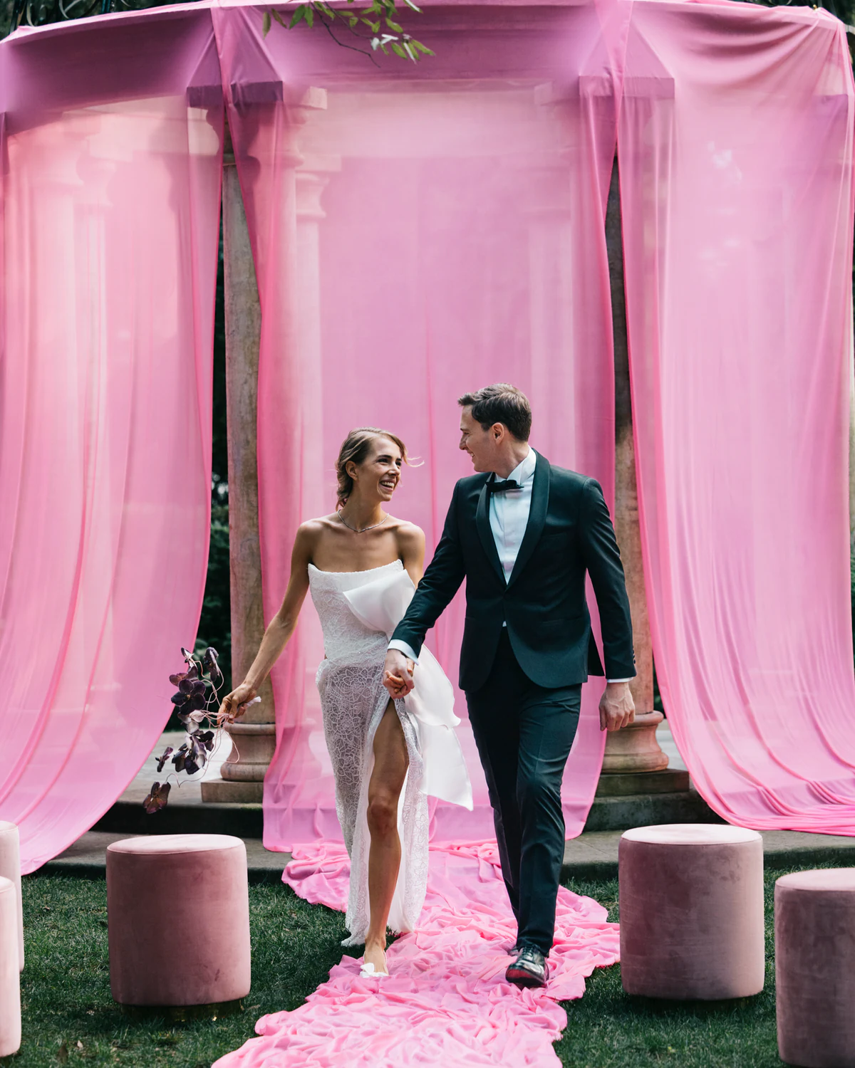 The couple walking on a pink carpet under the gazebo