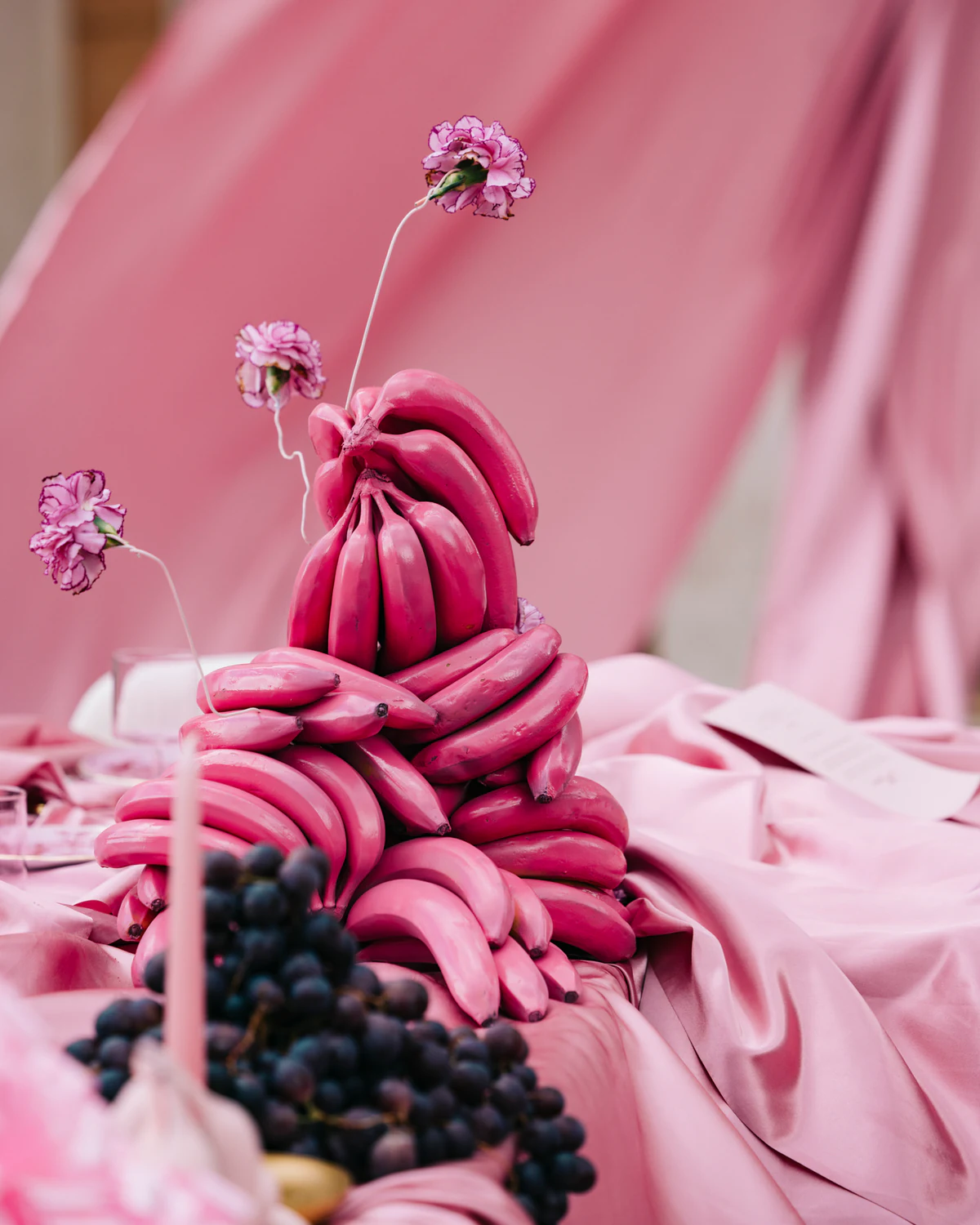 A centrepiece of pink bananas and grapes on pink silk