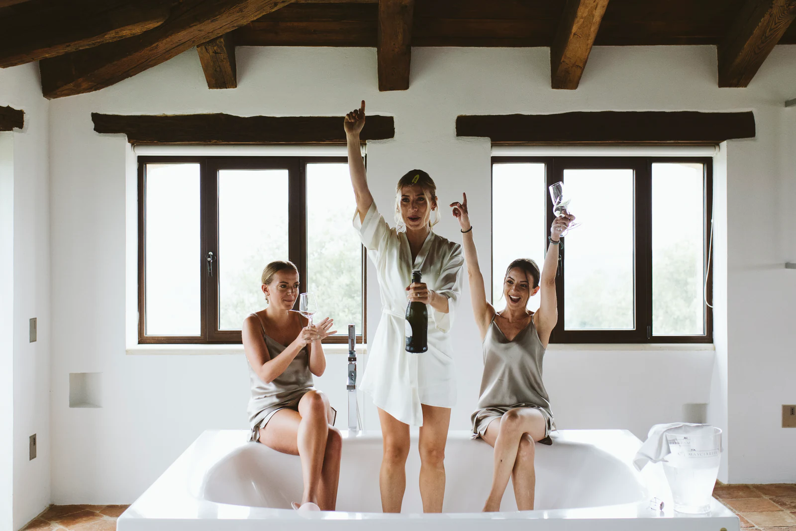 The bride and her friends celebrating with champagne in a bathtub
