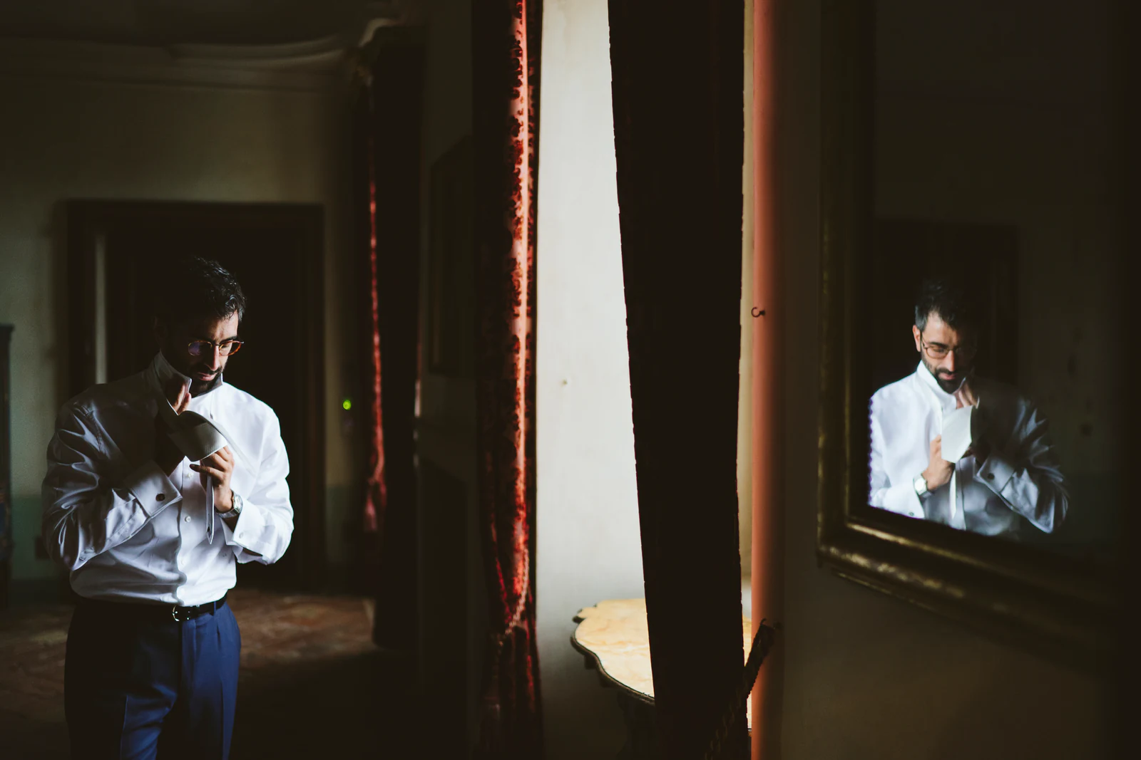 The groom getting dressed by a mirror