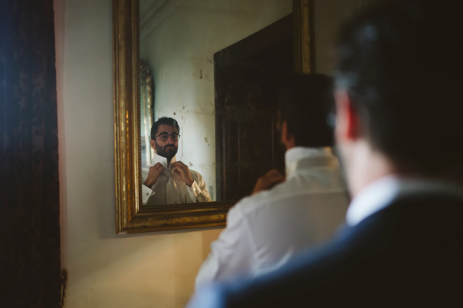 The groom reflected in a gilded mirror
