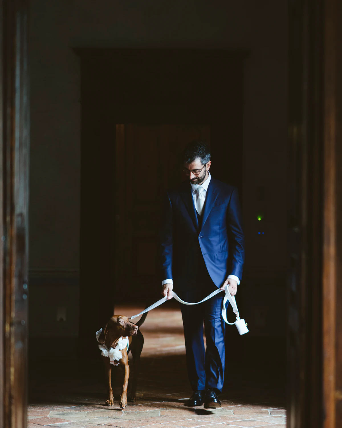The groom with a dog on a lead in a doorway