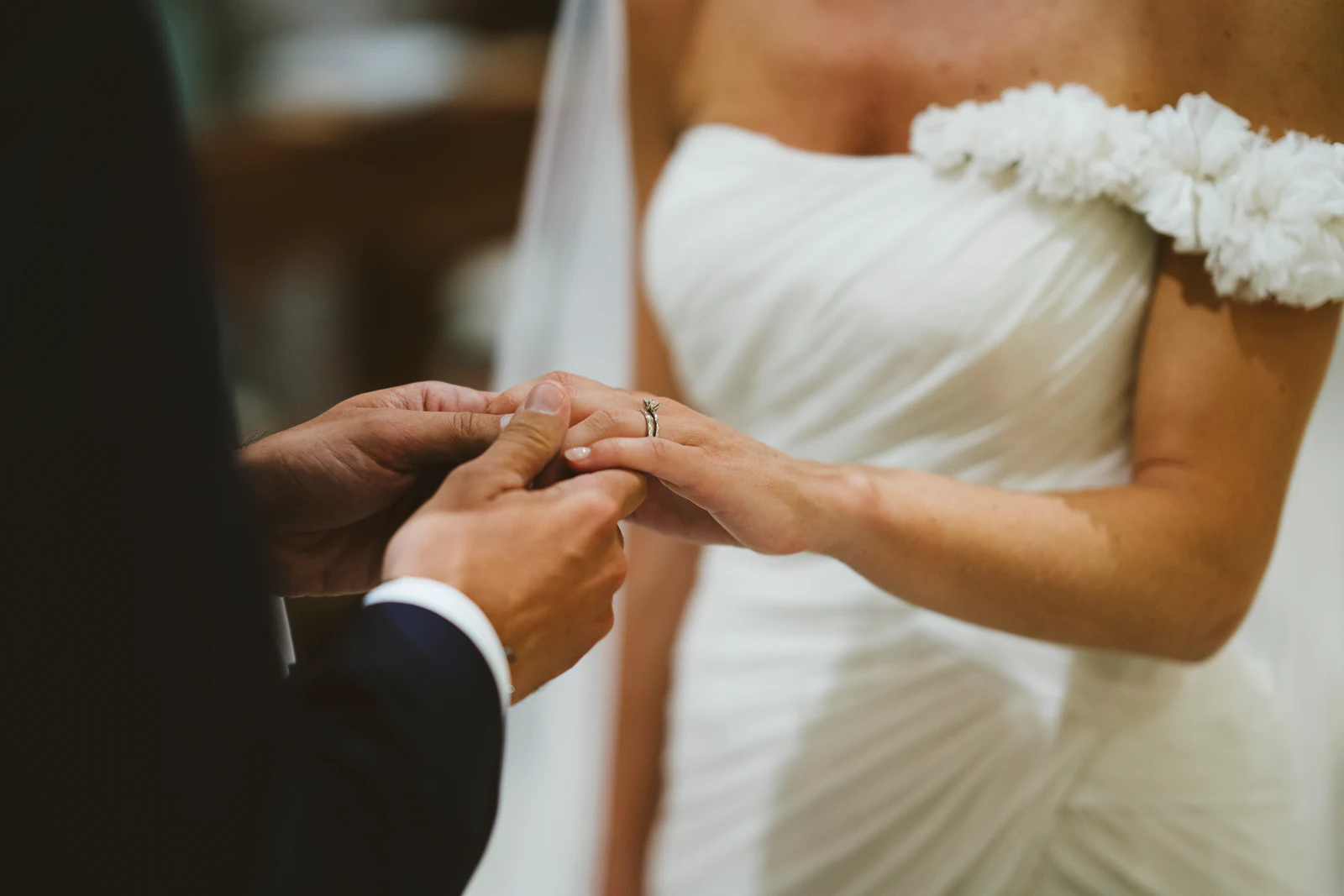 The groom slipping the ring onto the bride's finger