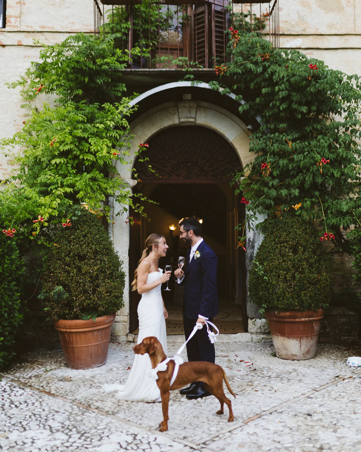 The couple with their dog in front of the arched doorway