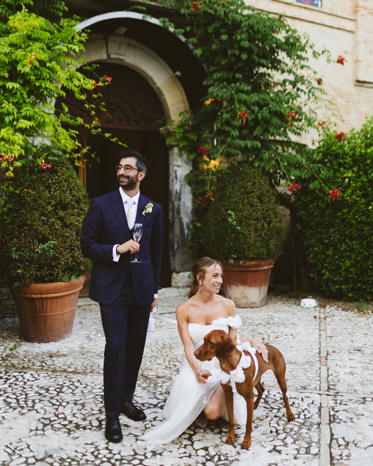 The couple with their dog at the castle door, the bride crouching beside it