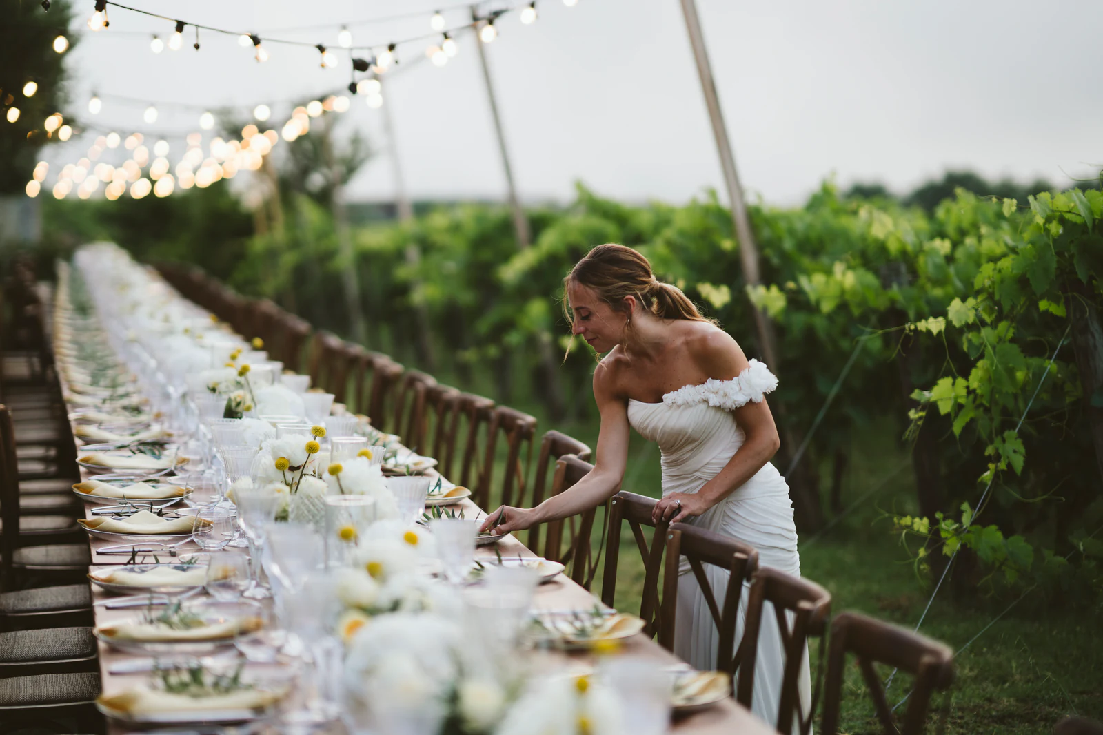 The bride looking at the long table under string lights