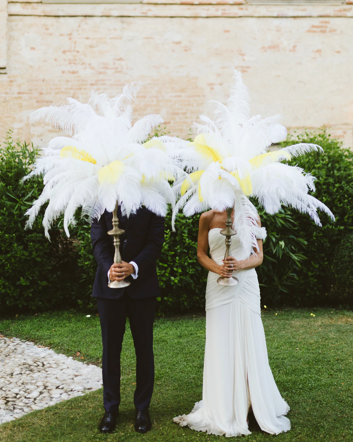 The couple hidden behind two large white feather fans