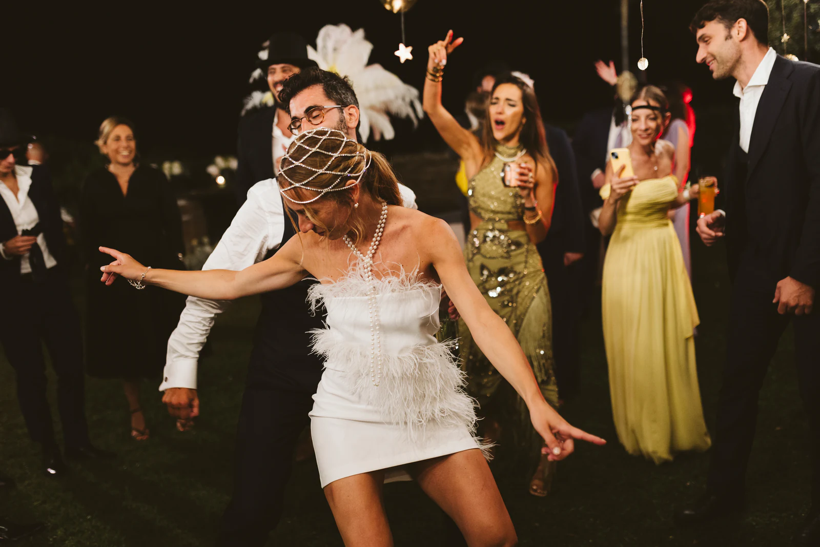 The bride in a feathered dress dancing with the guests