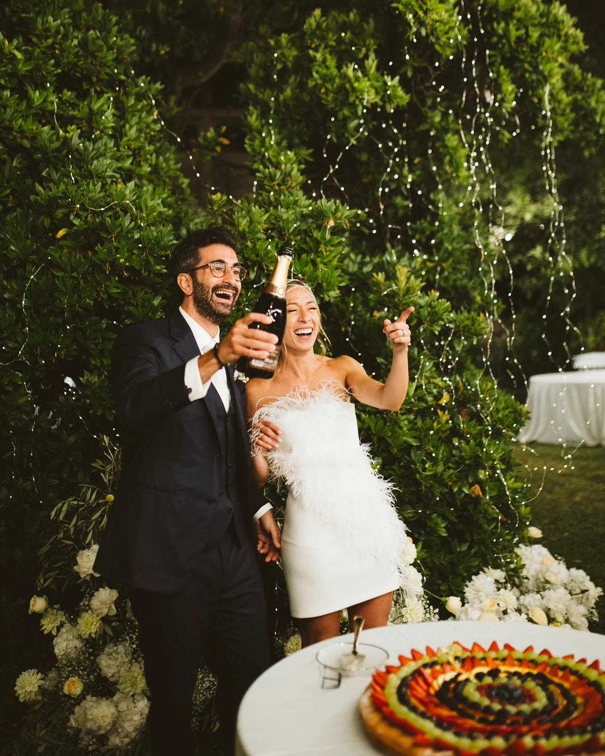 The couple laughing beside the cake